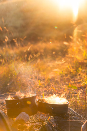 Touristic kettle on fire of burning campfire in camping in the hike. Cooking food in forest on wooden firewood.の写真素材