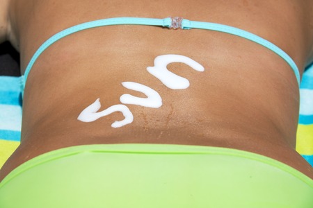 the word sun written with high protection suncream at the back of a teenage girl