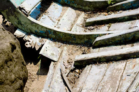 Old broken boat with a rock into itの写真素材