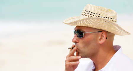 Man smoking cigarette on a beautiful beachの写真素材