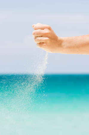 Falling sand in woman hands over seaの写真素材