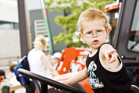 A little boy driving a tractor (look like is telling to his men: "GO TO WORK")の写真素材