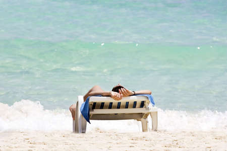 Woman sunbathing in a plastic chair on a beautiful beach in Cubaの写真素材