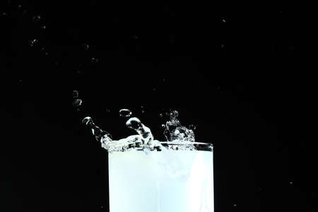 Splash of ice cubes in a glass of water, isolated on black background