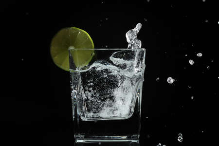 Water splash when lime ice cube falls out of the glassの写真素材