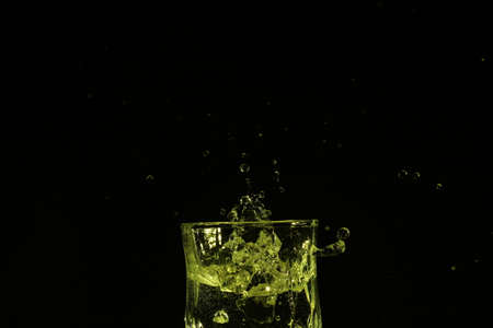 splash of water with falling ice cubes, whole colored yellowの写真素材
