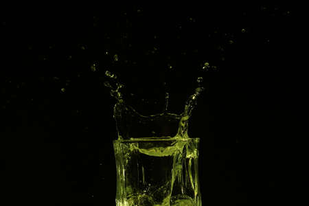 splash of water with falling ice cubes, whole colored yellowの写真素材