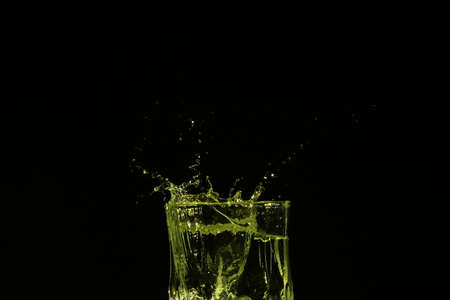 splash of water with falling ice cubes, whole colored yellowの写真素材