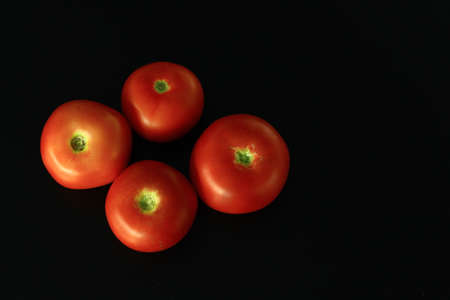 Four red Polish tomatoes on a black backgroundの写真素材