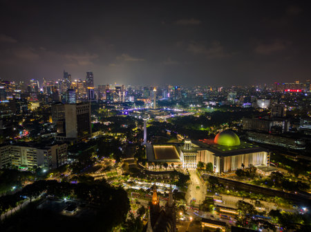 Aerial view of Jakarta city skyline with the illuminated Istiqlal Mosque and Jakarta Cathedral at night.の写真素材