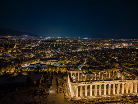 Aerial drone view of Athens city skyline at night with the illuminated Acropolis, Parthenon, ancient ruins, and urban lights in Greeceの写真素材