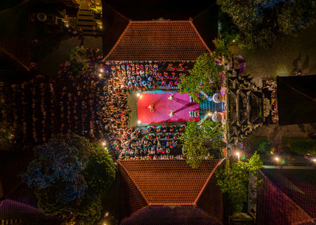 Aerial top view of traditional Balinese dance performance at night in Ubud, Bali Indonesia, with illuminated stage, audience, and temple architecture.の写真素材