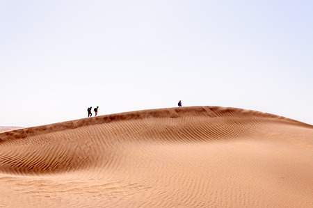 People walking on sand dunes, Hamada du Draa, moroccan stone desert (Morocco)の写真素材