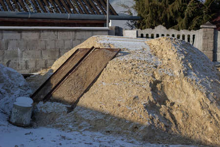 Construction of a private house. A pile of sand dusted with snow and a sieveの写真素材