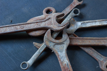 A close-up of weathered, rusty wrenches and a hook on a dark surface, showcasing their aged texture and industrial charm. Perfect for vintage tool enthusiasts.の写真素材
