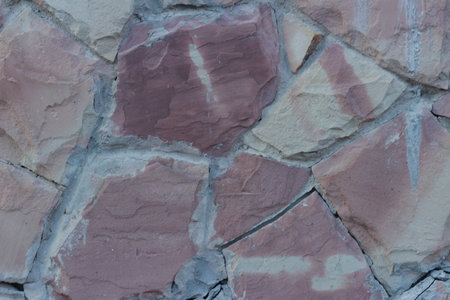 Texture of old brown facing stone tiles of arbitrary shape with cement joints