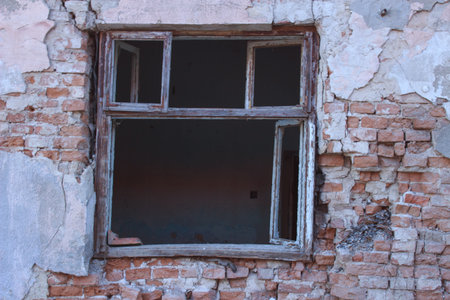 Old broken wooden window in a brick peeling wall of a vintage ruined houseの写真素材