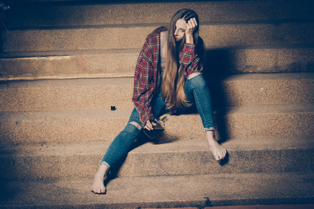 Young drunk woman sitting outside in night. Alcoholism and drug addiction lead to depression.の写真素材