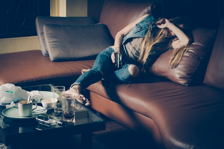 Young drunk woman on the sofa. Young drunk woman on the sofa. Alcoholism and drug addiction lead to depression.の写真素材