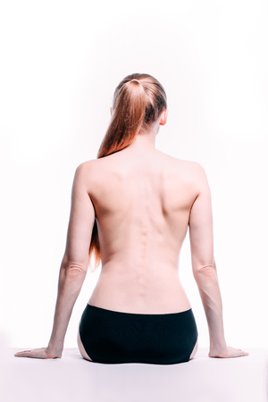 Beautiful athletic blond caucasian woman's body. Nude woman back. Naked woman in towel is sitting. Studio shot Back view, isolated on white background.の写真素材