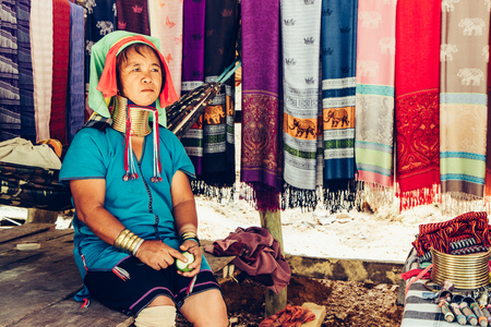 Long Neck Woman weave cloth in front her house in tribal village Northern Thailand.の写真素材