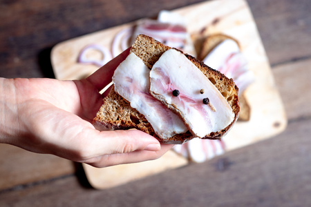 Lard with black bread on a wooden board and handの写真素材