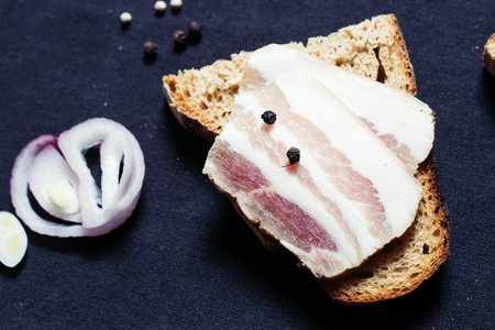 Sandwich with lard with black bread on the tablecloth on the wooden table
