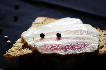 Sandwich with lard with black bread on the tablecloth on the wooden table