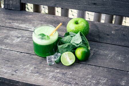 Green apple smoothie in glass and kale leaves on wooden tableの写真素材