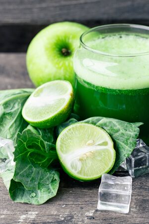 Green apple smoothie in glass and kale leaves on rustic wooden table. Summer Detox shake backgroundの写真素材
