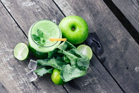 Green apple smoothie in glass and kale leaves on rustic wooden table. Summer Detox shake backgroundの写真素材