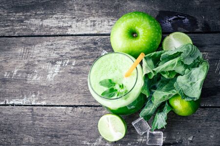 Green apple smoothie in glass and kale leaves on rustic wooden table. Summer Detox shake backgroundの写真素材