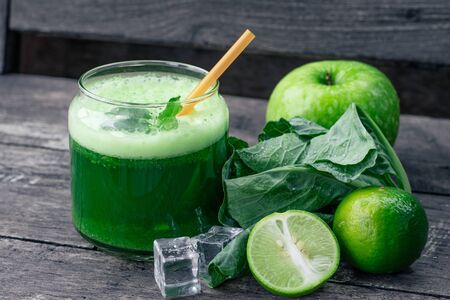 Green apple smoothie in glass and kale leaves on wooden tableの写真素材