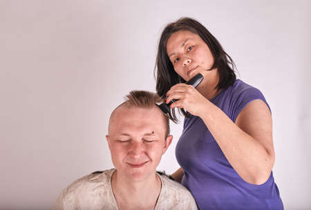 Wife doing haircut for husband at home while Covid-19 quarantine. Self isolation family lifestyle.