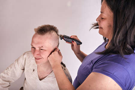 Wife doing haircut for husband at home while Covid-19 quarantine. Self isolation family lifestyle.