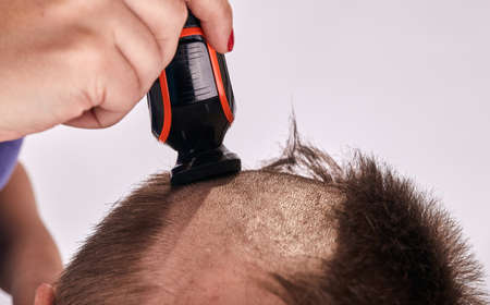 Woman doing haircut for man at home while Covid-19 quarantine. Self isolation family lifestyle.の写真素材