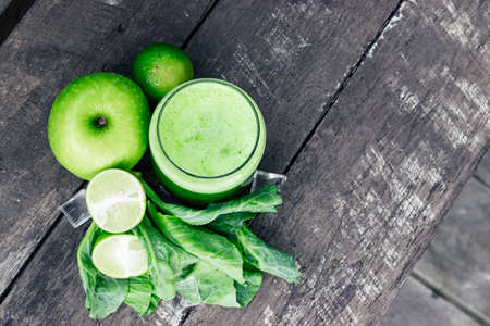Green apple smoothie in glass and kale leaves on wooden tableの写真素材