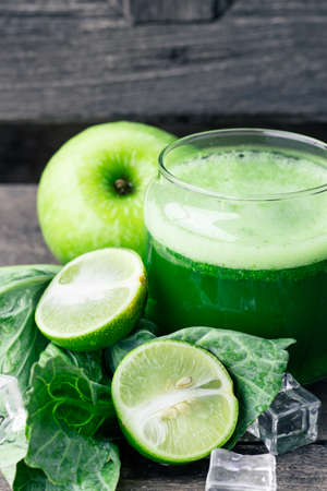 Green apple smoothie in glass and kale leaves on rustic wooden table. Summer Detox shake backgroundの写真素材