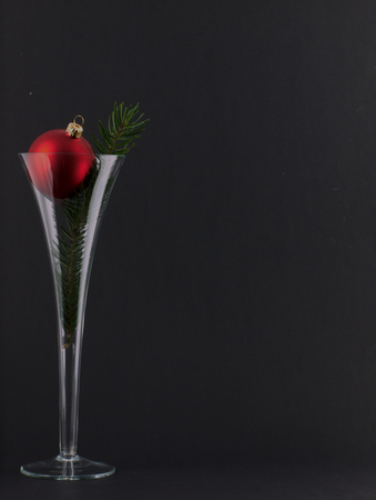 Glass of champagne and a glass bauble Christmas Tree. With a sprig of pine. On a black background.の写真素材
