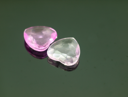 Two small bright hearts on a dark background with mirror reflection.の写真素材