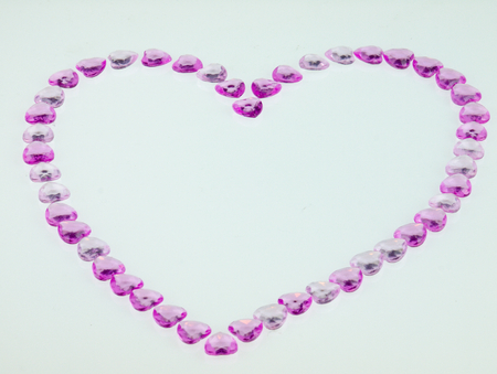 Heart arranged with small purple hearts on a white background.の写真素材