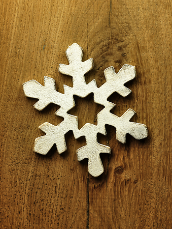 Christmas decoration in the form of a wooden snowflake on the wooden background.の写真素材