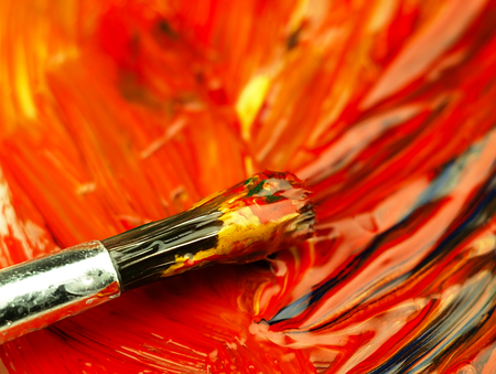 Paints and brush up on the pallet. Different colors mixed in multi-colored mass. Visible texture...