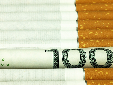 Smoking is expensive habit. Cigarettes on money background.の写真素材