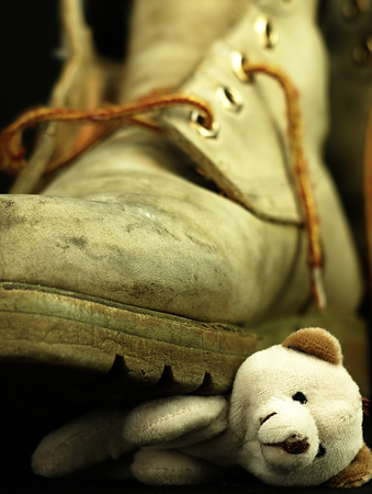 Teddy bear under the old, dirty and heavy military boot. The view from the perspective of frogs.の写真素材