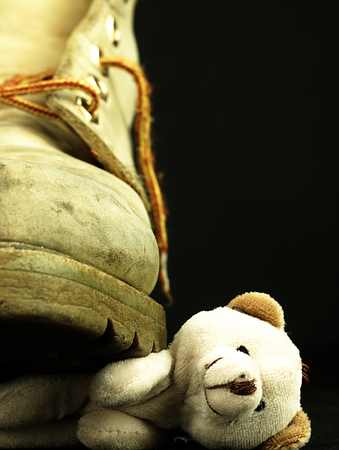 Teddy bear under the old, dirty and heavy military boot. The view from the perspective of frogs.の写真素材