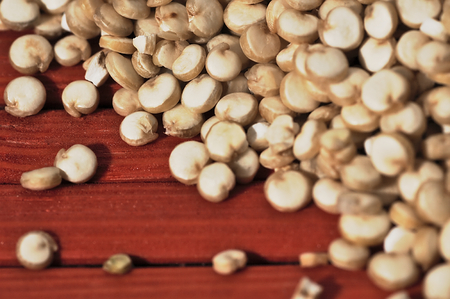 Grain quinoa scattered on the red, wooden surface.の写真素材