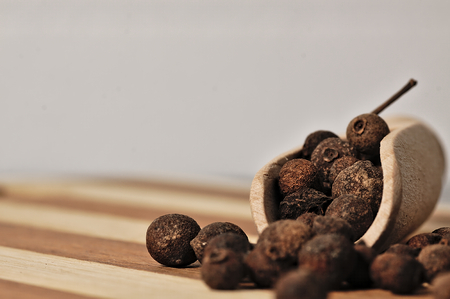 Dried allspice on a wooden, two-tone surface.