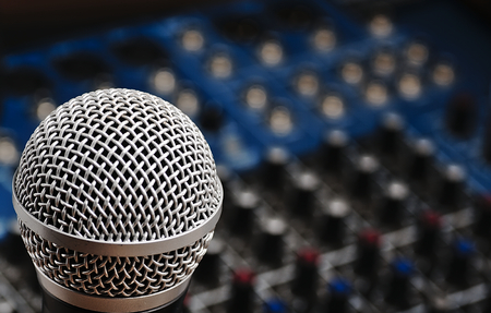 Sound console with buttons in the background and a dynamic microphone in the foreground.