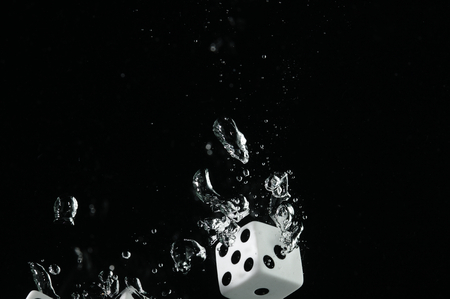 Dice playing in the water. Visible splash and air bubbles.の写真素材